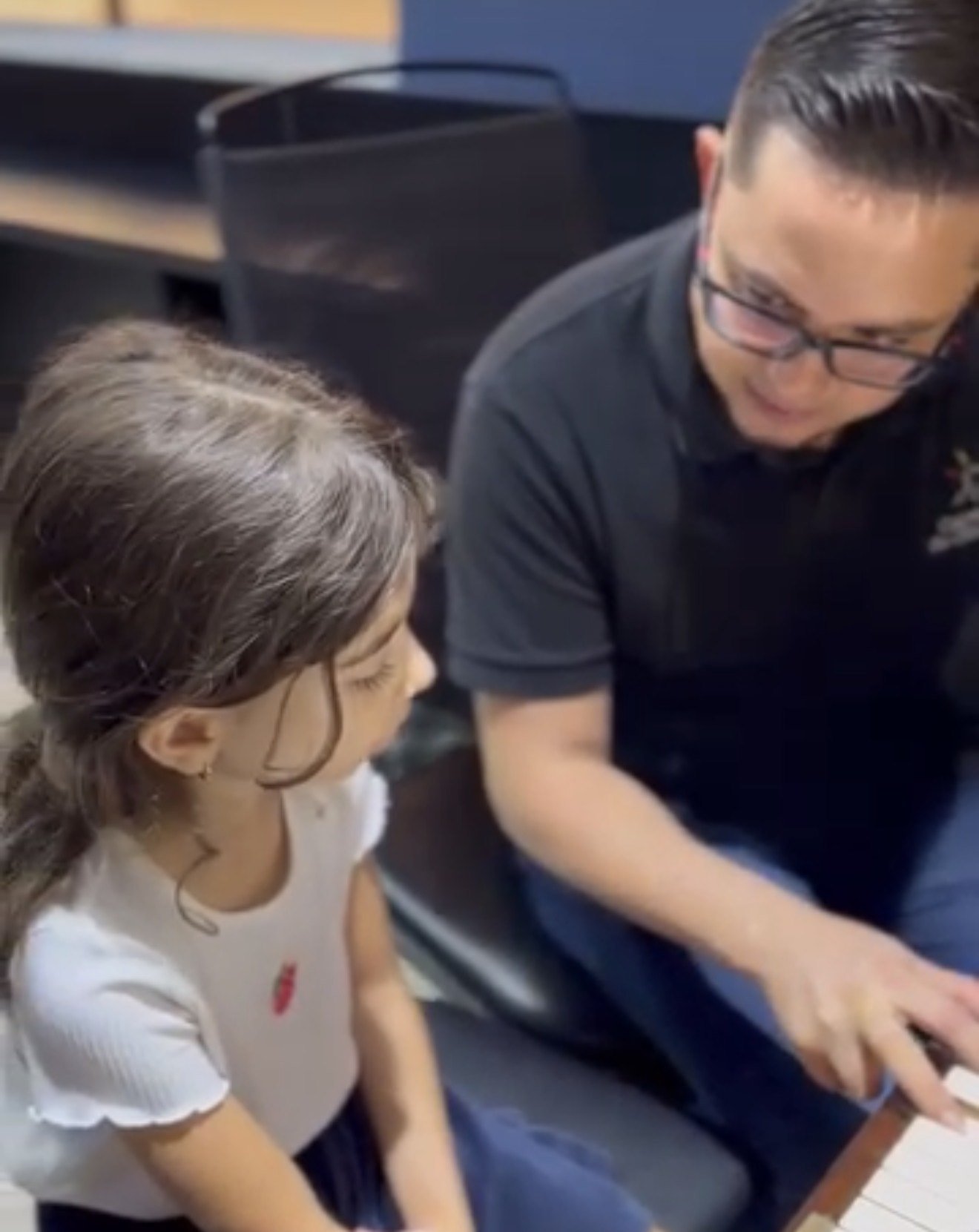 Professor conduzindo aula individual de piano para uma criança com TEA